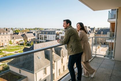 Jeune couple souriant sur un balcon moderne à Saint Brieuc