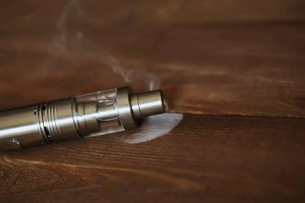Cigarette électronique sur une table en bois avec de la vapeur entourante