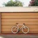 white bike leaning on brown roller shutter